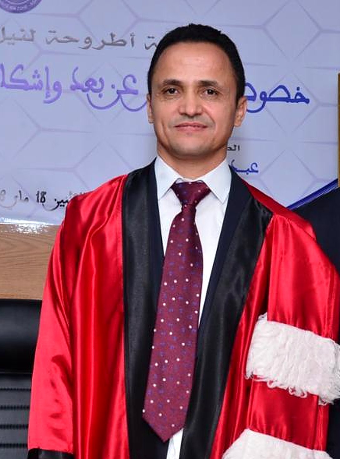 الأستاذ عبد السلام مزيغي ببذلة الدكتوراه الحمراء يوم مناقشة أطروحته